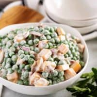 Green pea salad with cheese in a white bowl.