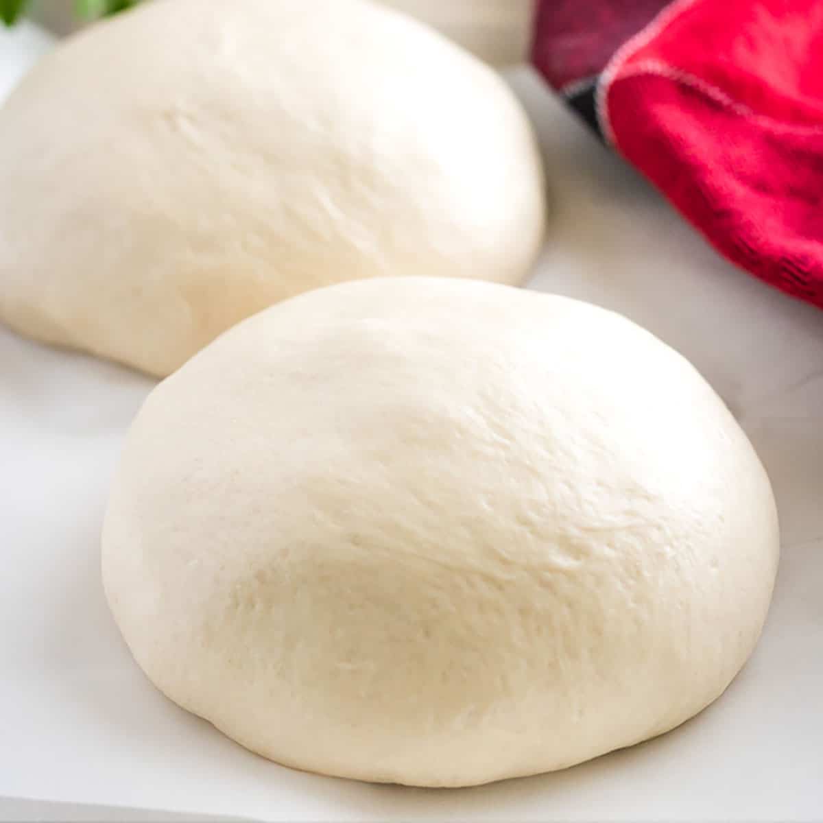 Homemade pizza dough on a piece of parchment paper.