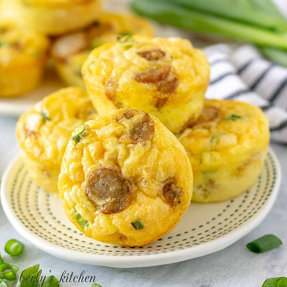 Plate of sausage, egg, and cheese muffins surrounded by chopped green onions.