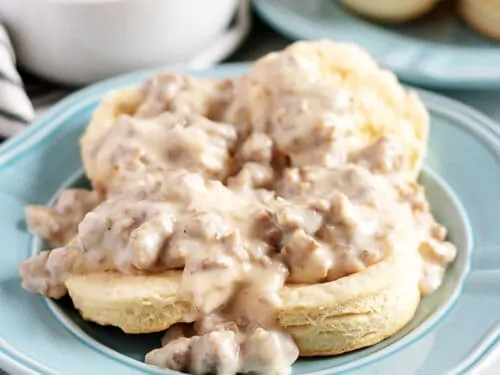 Biscuits and sausage gravy on a blue plate.
