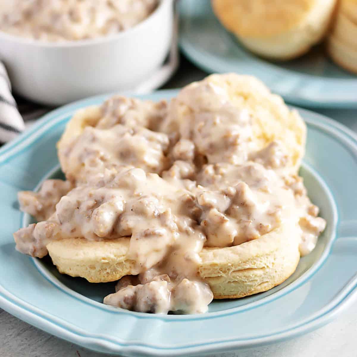 Biscuits and sausage gravy on a blue plate.