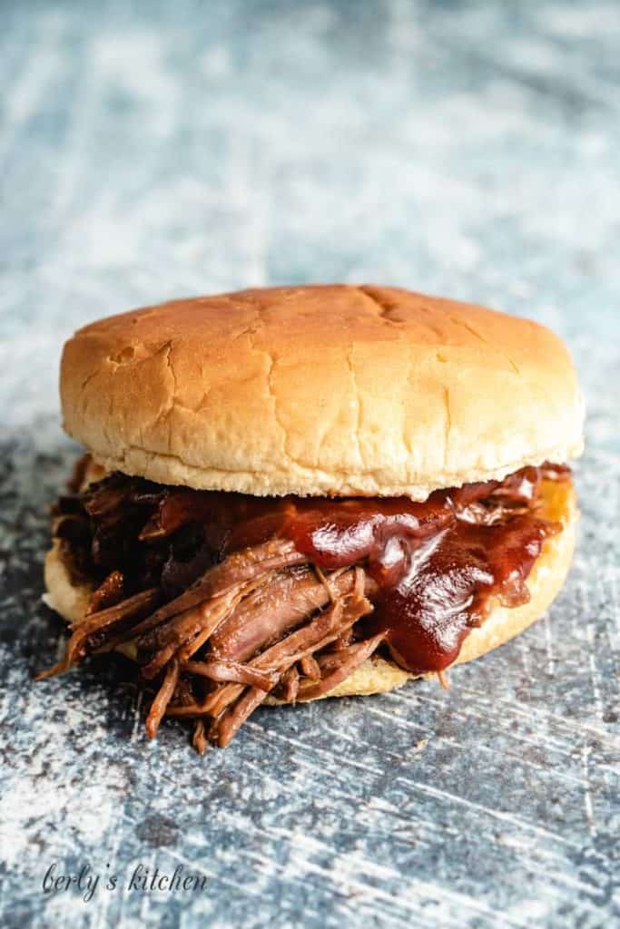 A BBQ beef sandwich served with BBQ sauce.
