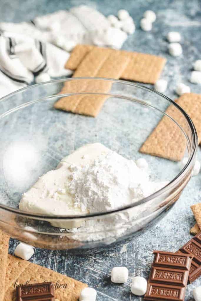 Powdered sugar and softened cream cheese in a mixing bowl.