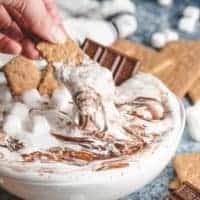 A graham cracker being dipped into the dessert dip.