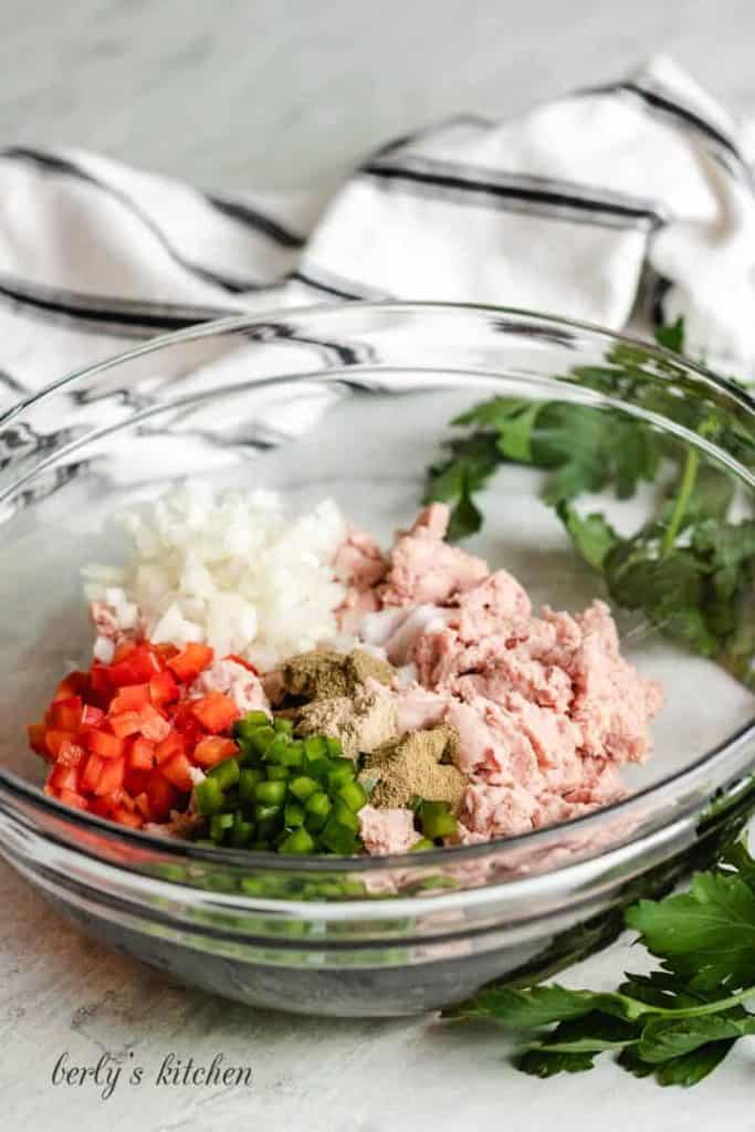 Raw ground turkey, peppers, onions, and spices in a mixing bowl.
