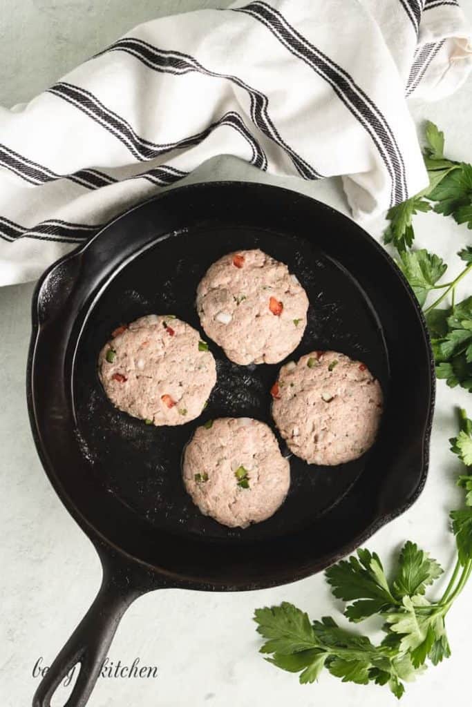 The meat mixture, formed into patties. and placed into a skillet to cook.