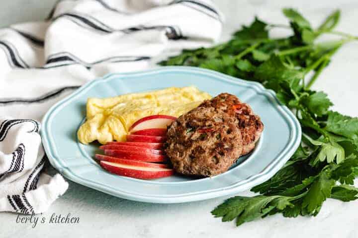 Cooked ground turkey sausage on a blue plate with apples and eggs.