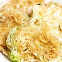 Four pieces of cooked cabbage on a white plate.