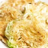 Four pieces of cooked cabbage on a white plate.