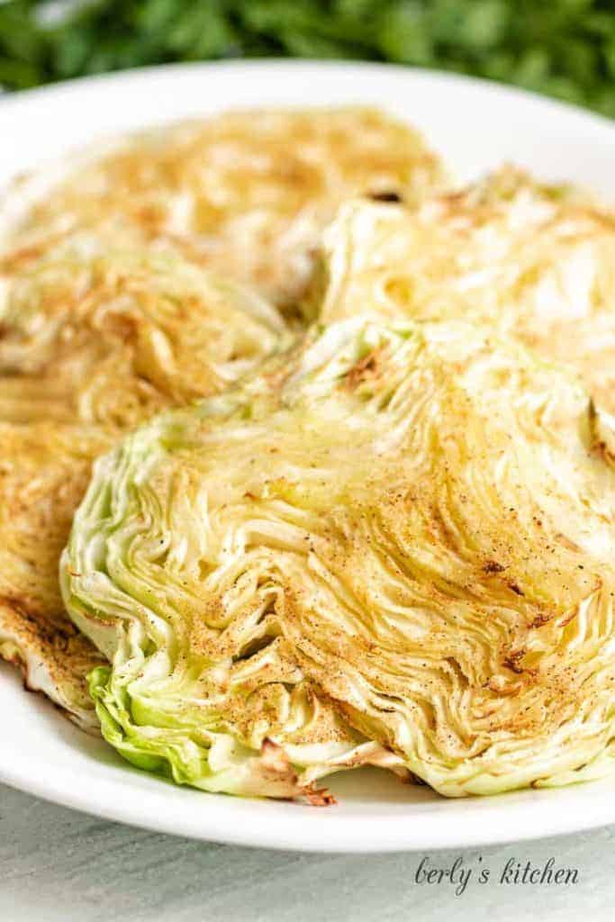 Four pieces of cooked cabbage on a white plate.