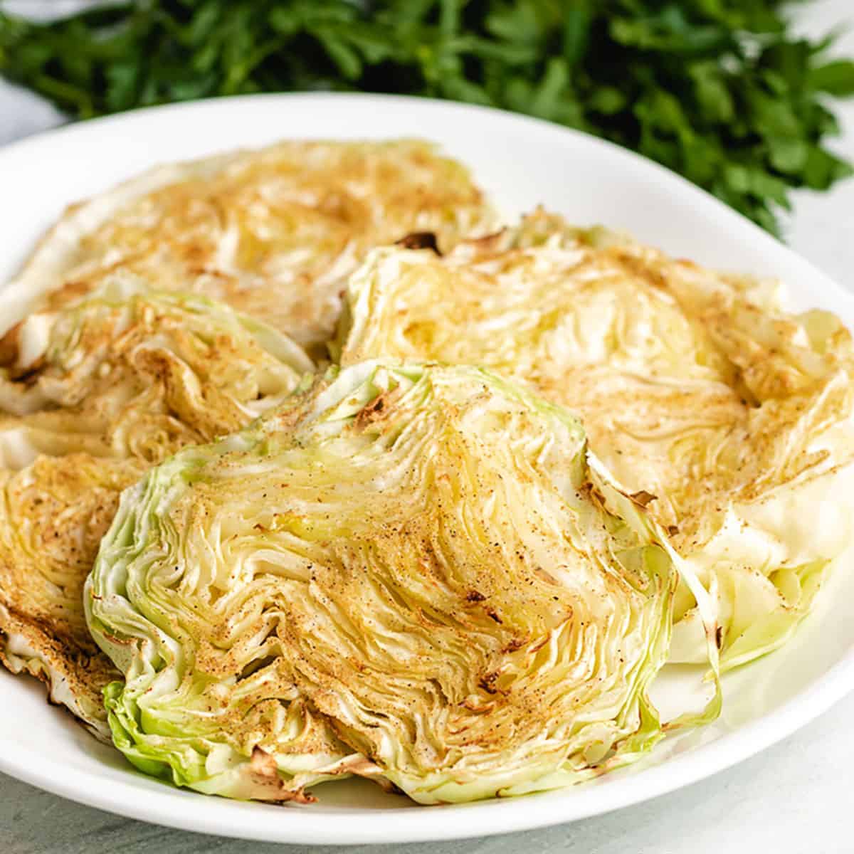 Four seasoned air fryer cabbage steaks on a plate.