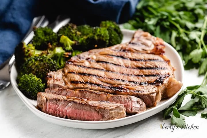 A sliced steak served on a plate with broccoli.