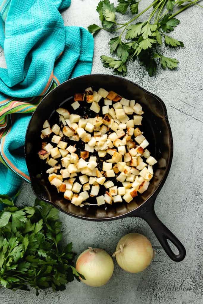 Diced potatoes cooking in a cast iron skillet.