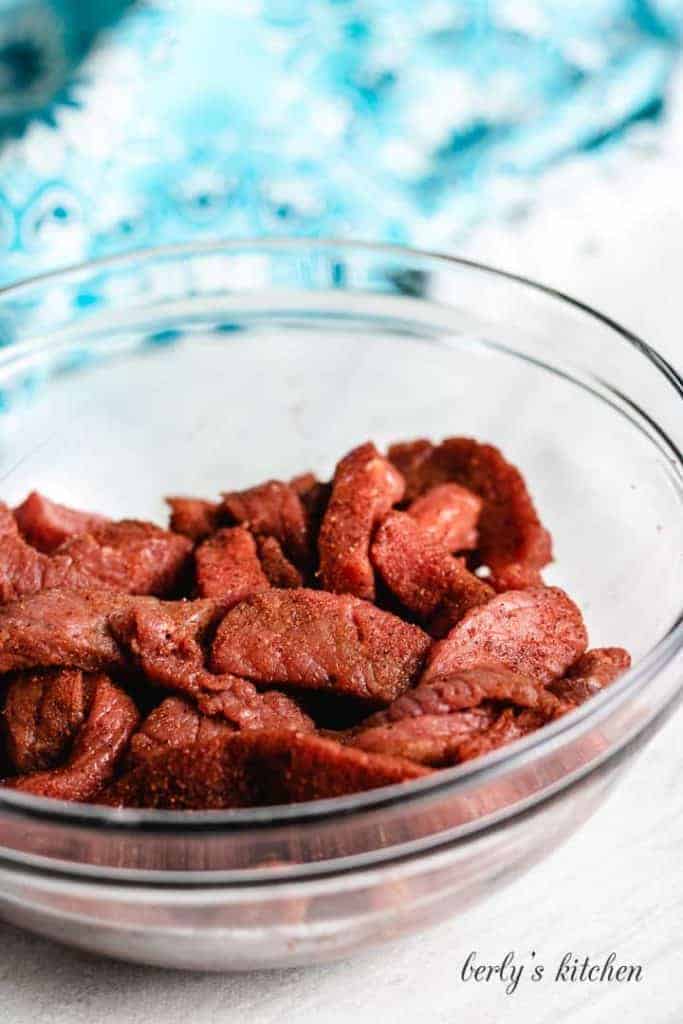 The spices and beef tossed together in a bowl.