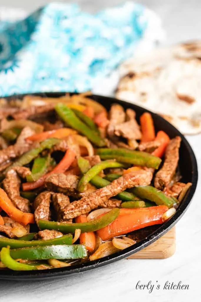 The cooked beef, peppers, and onions in the cast iron skillet.