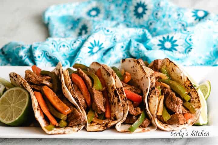 Four flat iron steak fajitas served with fresh limes.