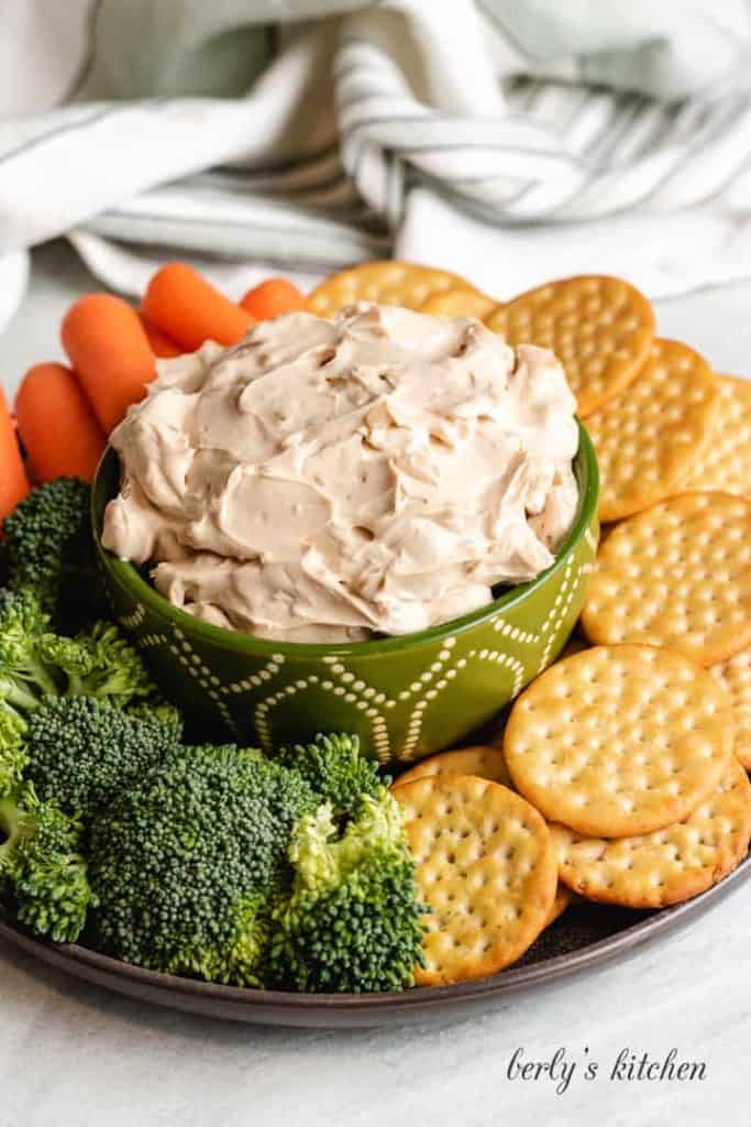 Dip in a decorative bowl served with crackers and vegetables.
