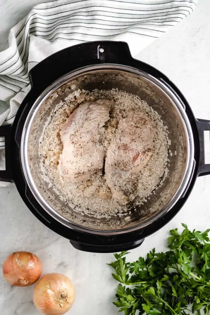 Chicken, onions, rice, and broth in the Instant Pot.