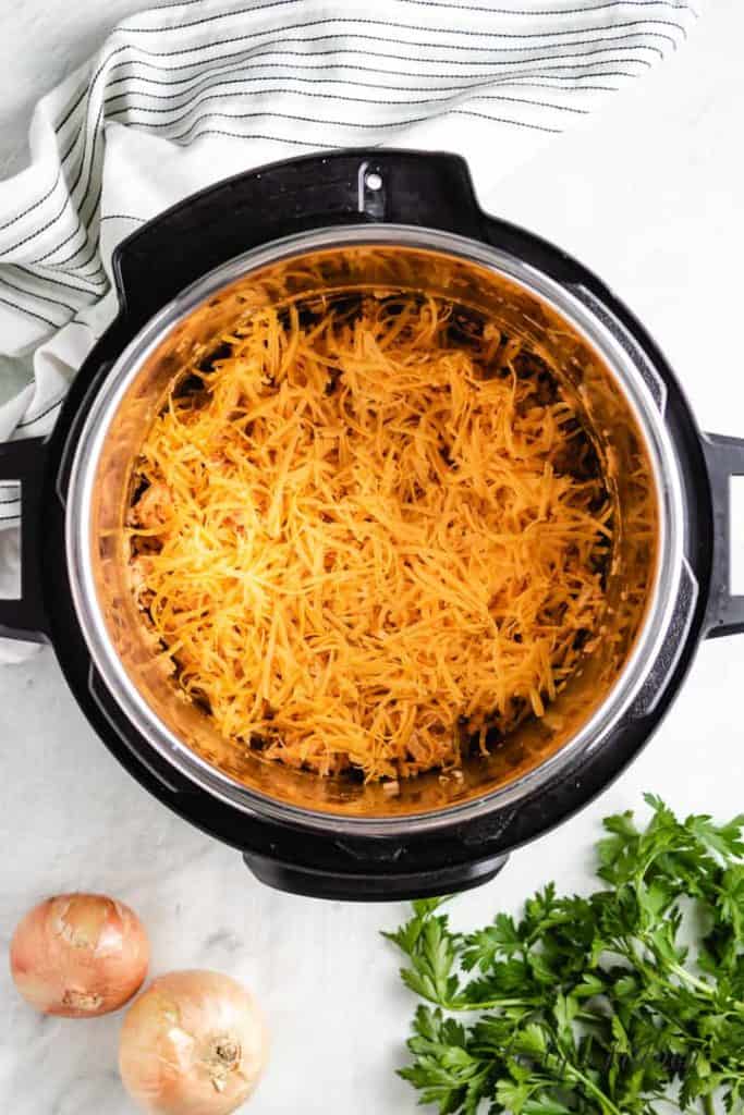 Shredded cheese on buffalo chicken and rice in the Instant Pot.