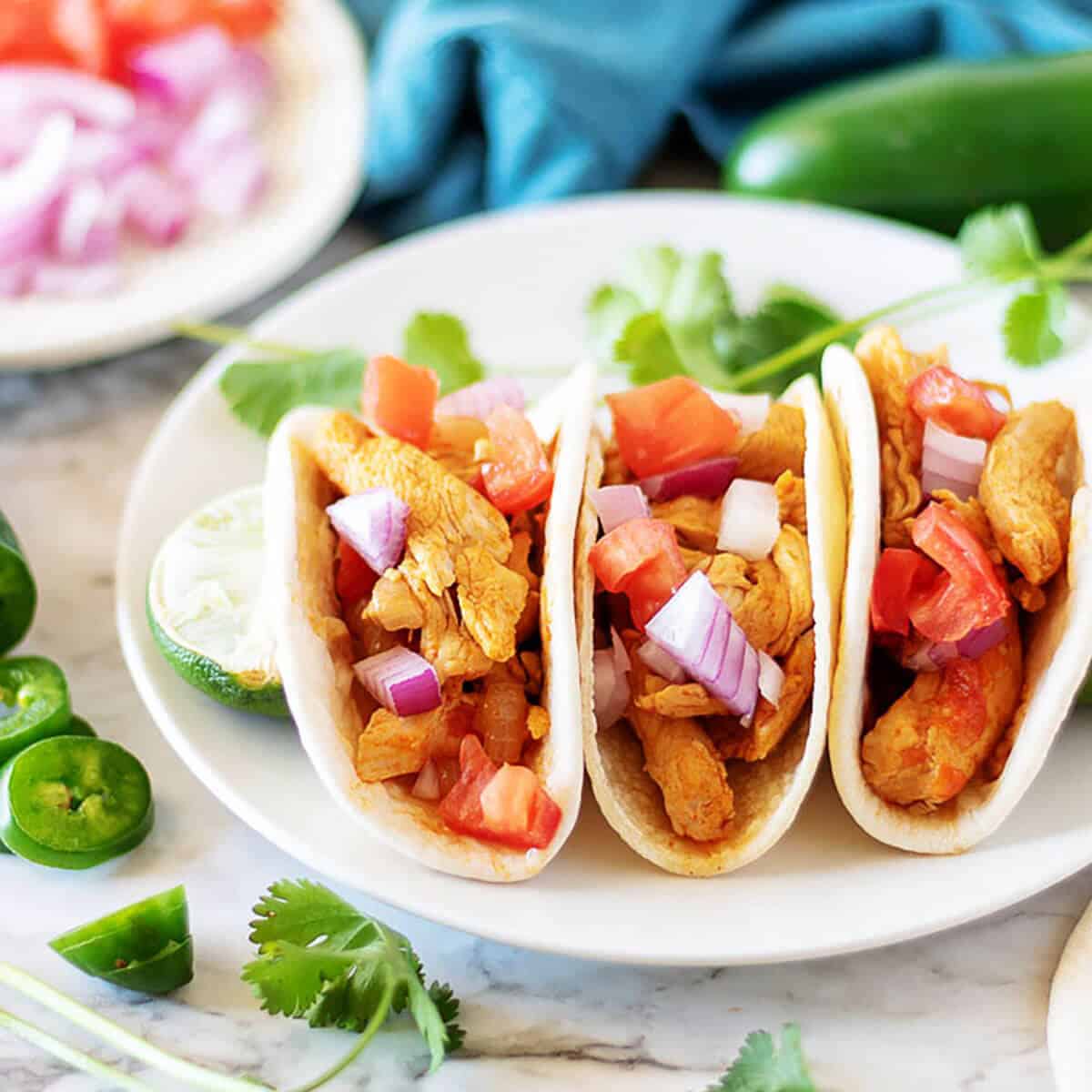 Three Instant Pot street tacos with chicken filling and diced onions.