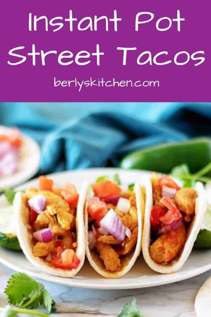 Three street tacos with chicken topped with onions and tomatoes.