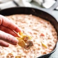 A chip being dipped into the warm cheese dip.