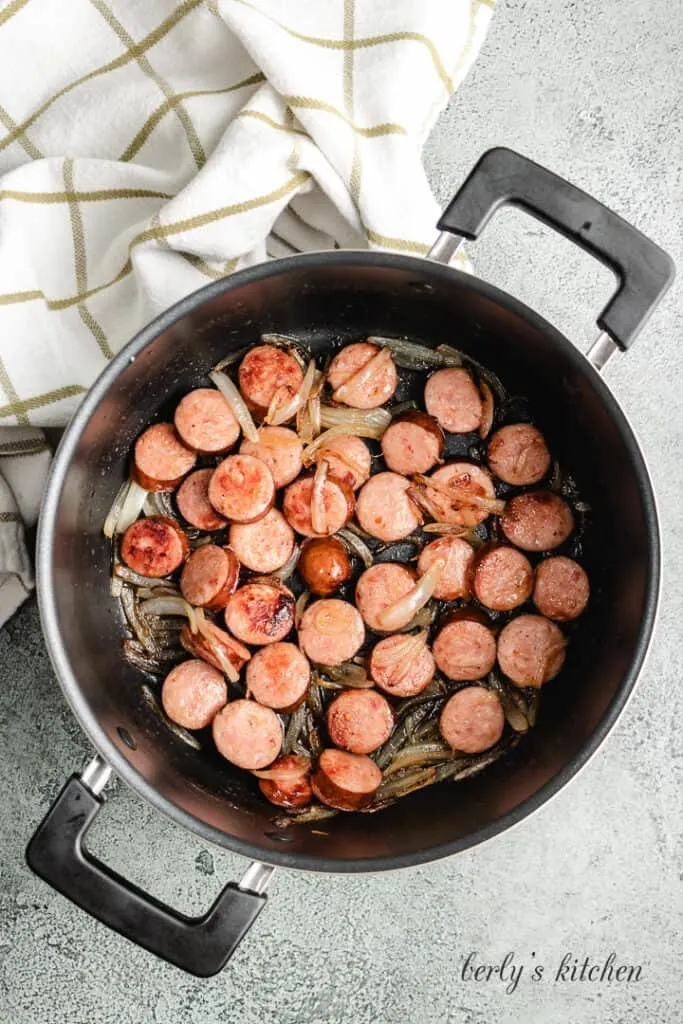 Sausage and onions cooking in a pot.