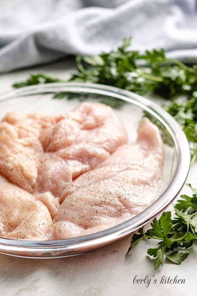 Raw chicken sprinkled with salt and pepper.