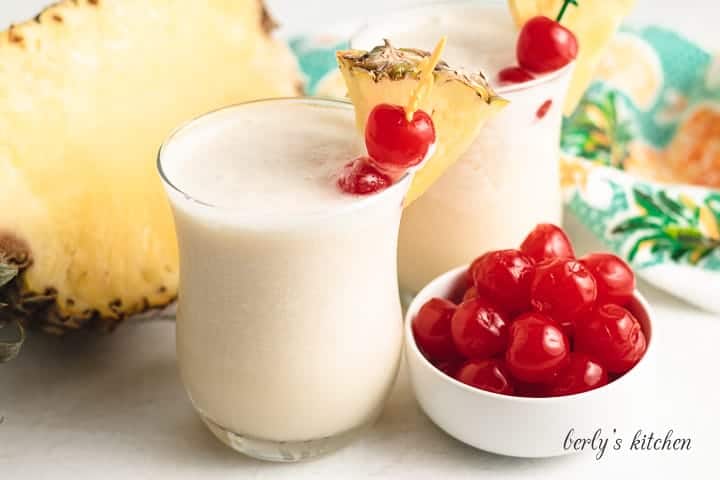 Two henny coladas garnished with cherries and pineapple.