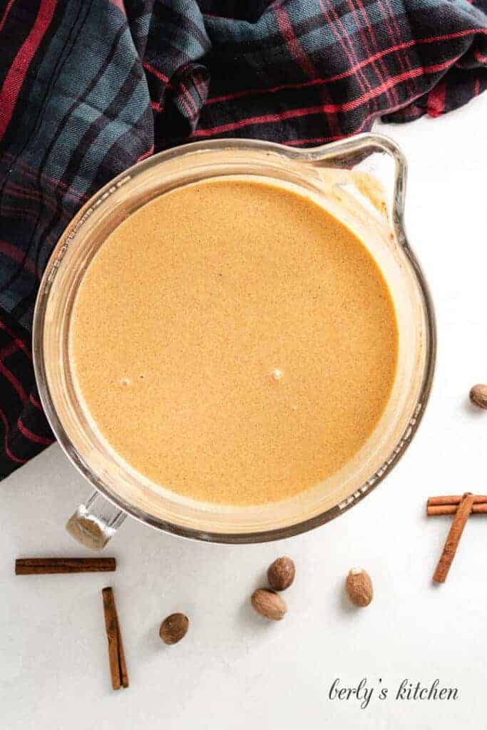 Pumpkin and other ingredients combined in a glass measuring cup.