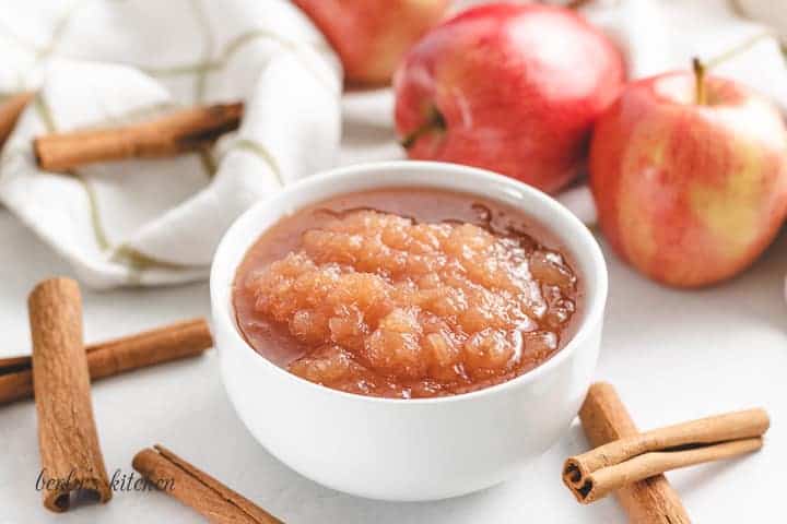 The applesauce surrounded by fresh cinnamon sticks and apples.