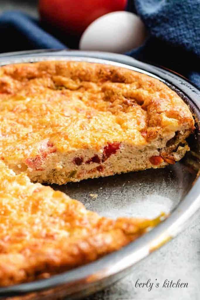 A slice of the quiche has been removed from the pie.