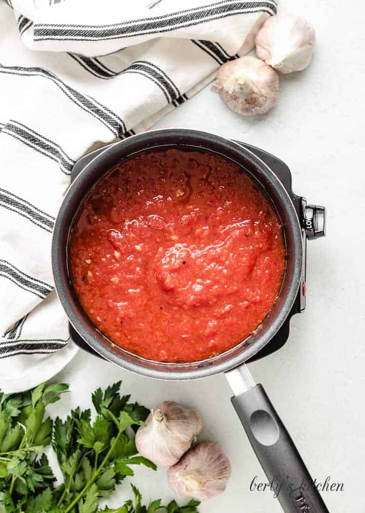 Crush tomatoes and other ingredients added to the saucepan.