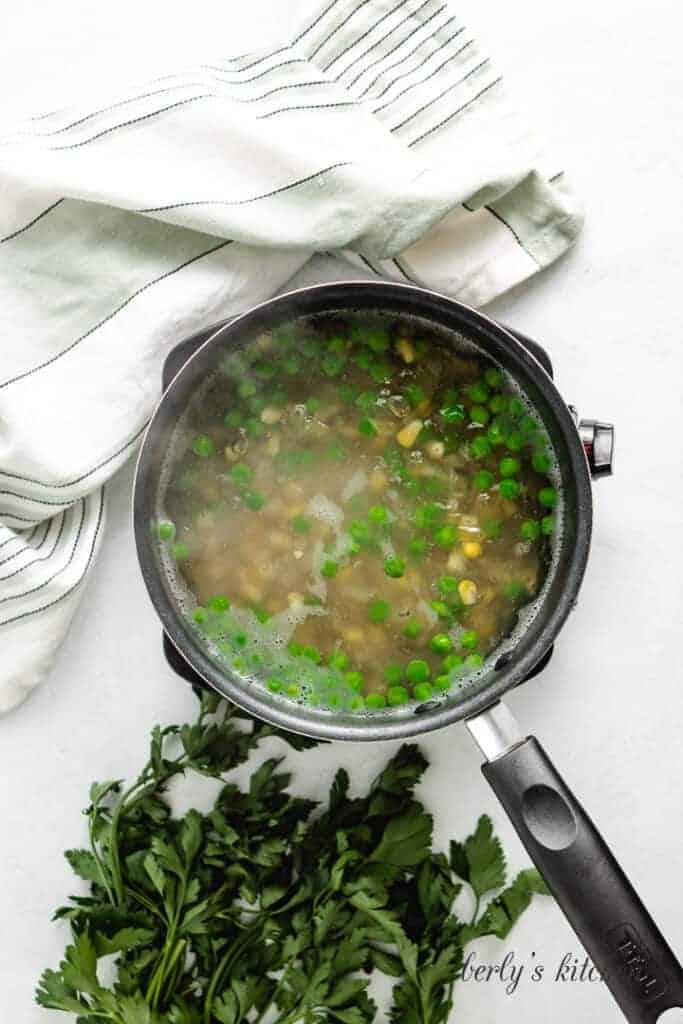 The pasta and veggies boiling in a saucepan.