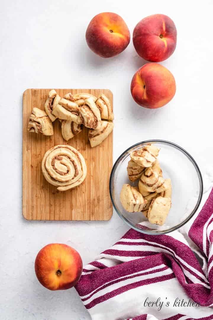 Cinnamon rolls on a cutting board and in a measuring cup.