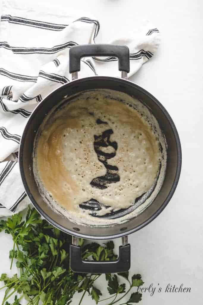 Butter, flour and other ingredients cooking in a pot.