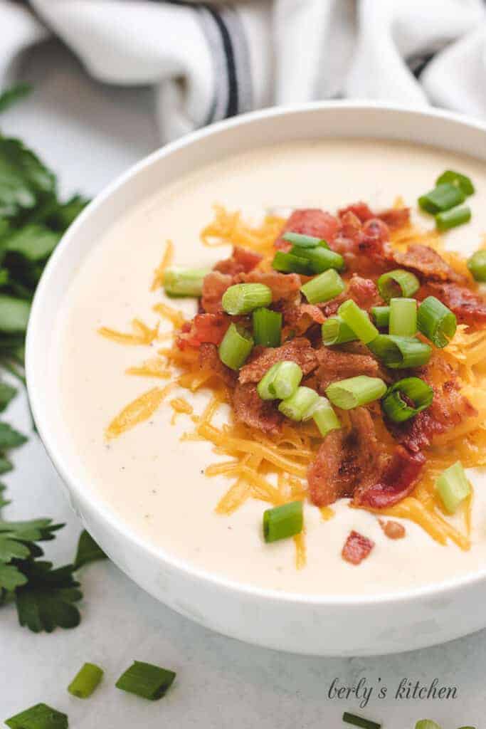 Baked potato soup garnished with onions, bacon, and cheese.