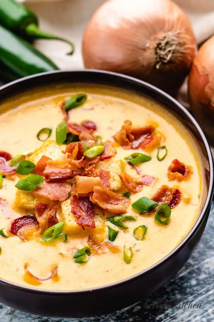 Creamy JalapeÑO Beer Cheese Soup Diced green onions and crispy bacon atop the soup.