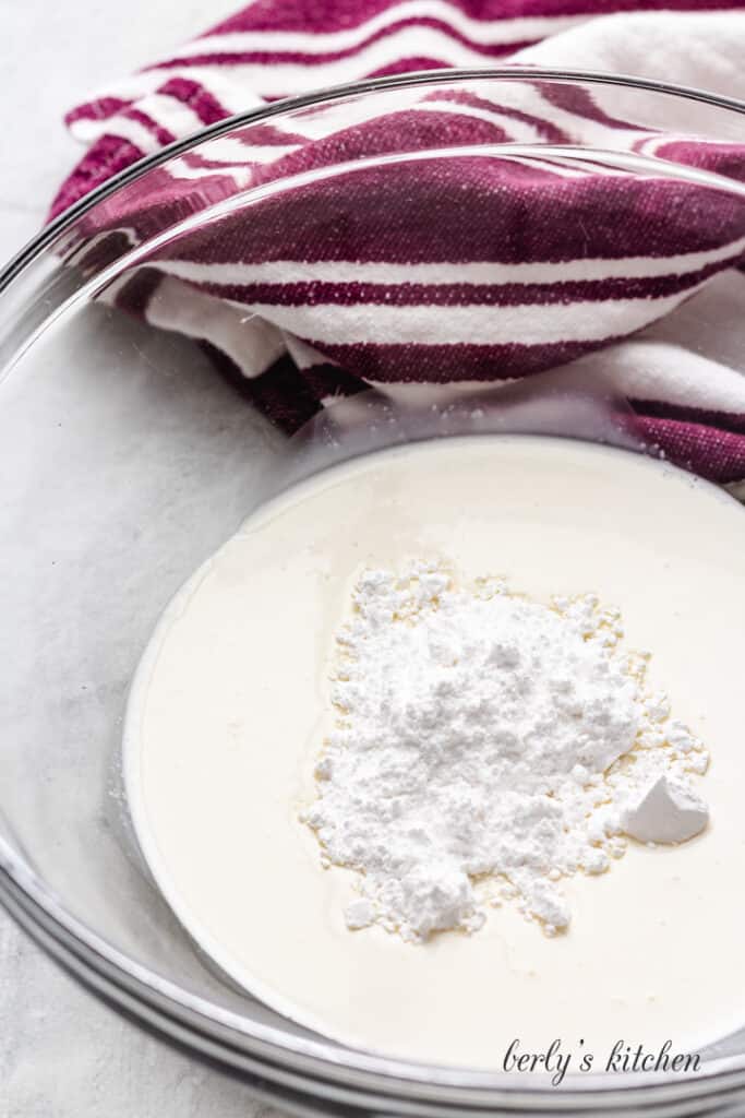 Powdered sugar and heavy cream in a mixing bowl.