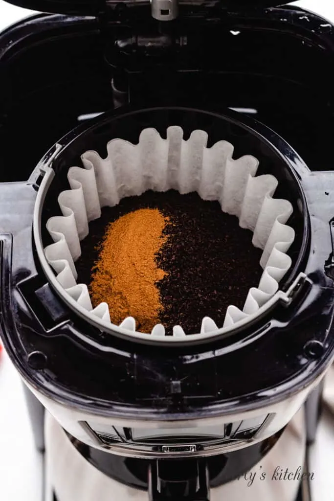 Ground coffee and cinnamon in a coffee maker.