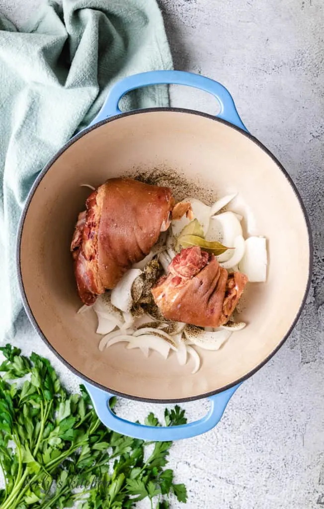 Pork, onions, and other ingredients in a pot.