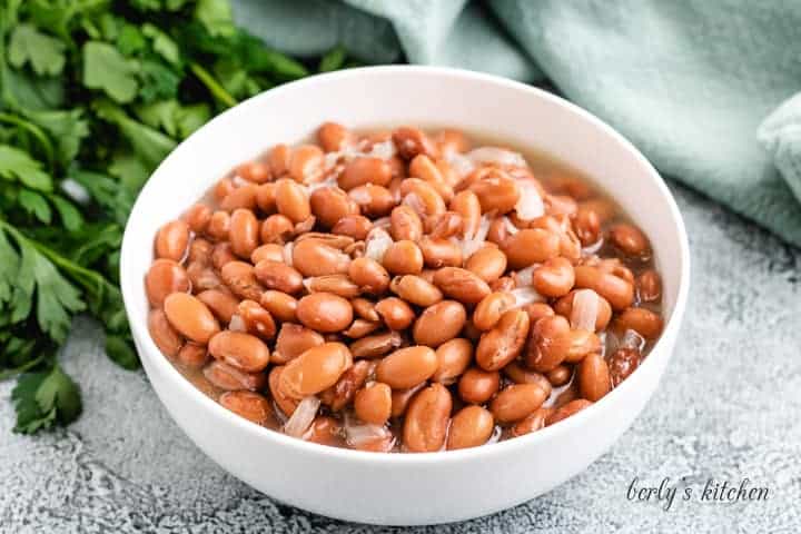 Ham hock and beans served in white bowl.