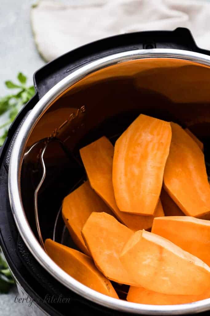 Slices, raw sweet potatoes in a pressure cooker.