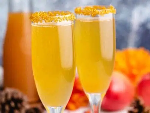 Two apple cider mimosas in champagne glasses.