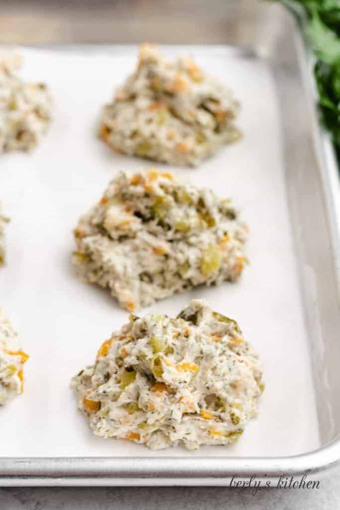 Raw drop biscuits on a sheet pan.