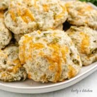 A round plate loaded with cheddar dill biscuits.