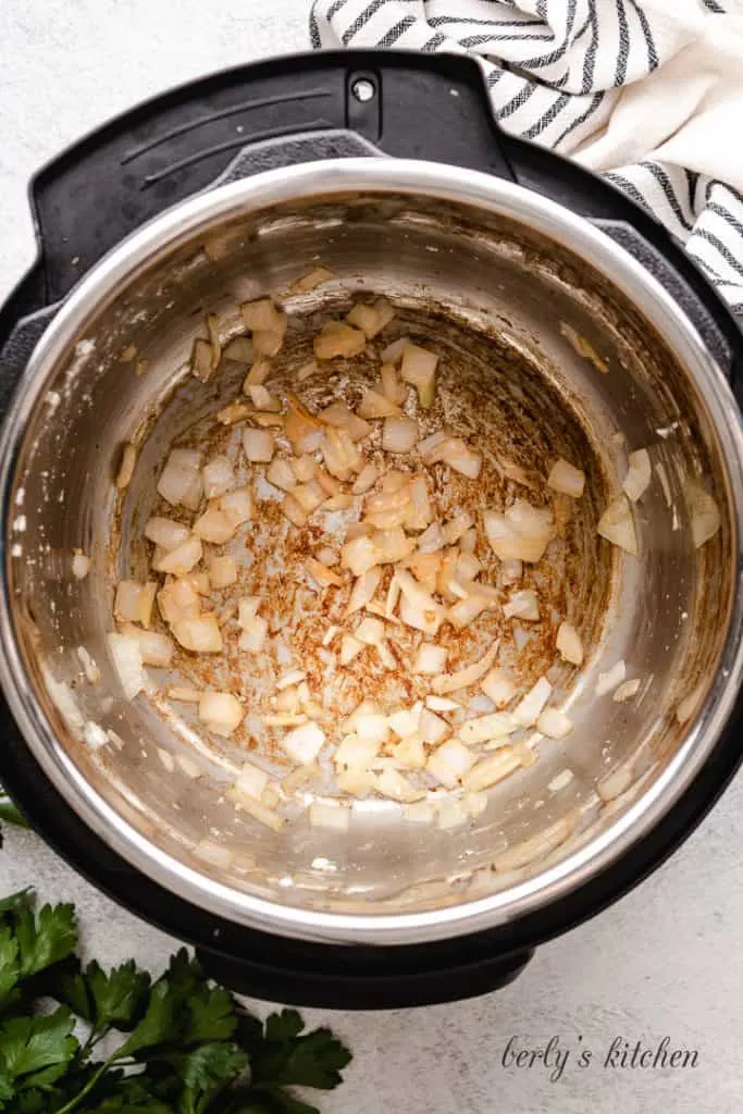 Diced white onion cooking in the pressure cooker.