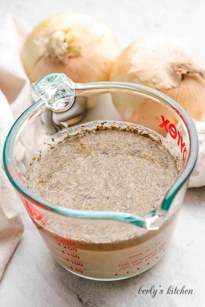 Broth, mustard, and other ingredients combined in a measuring cup.