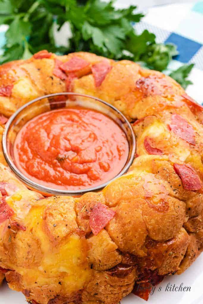 Pizza bread on a serving platter with marinara sauce.