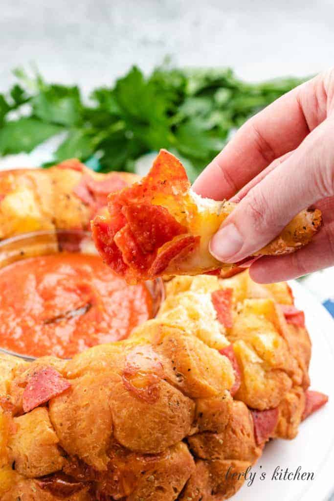 A piece of pizza bread being lifted from the plate.